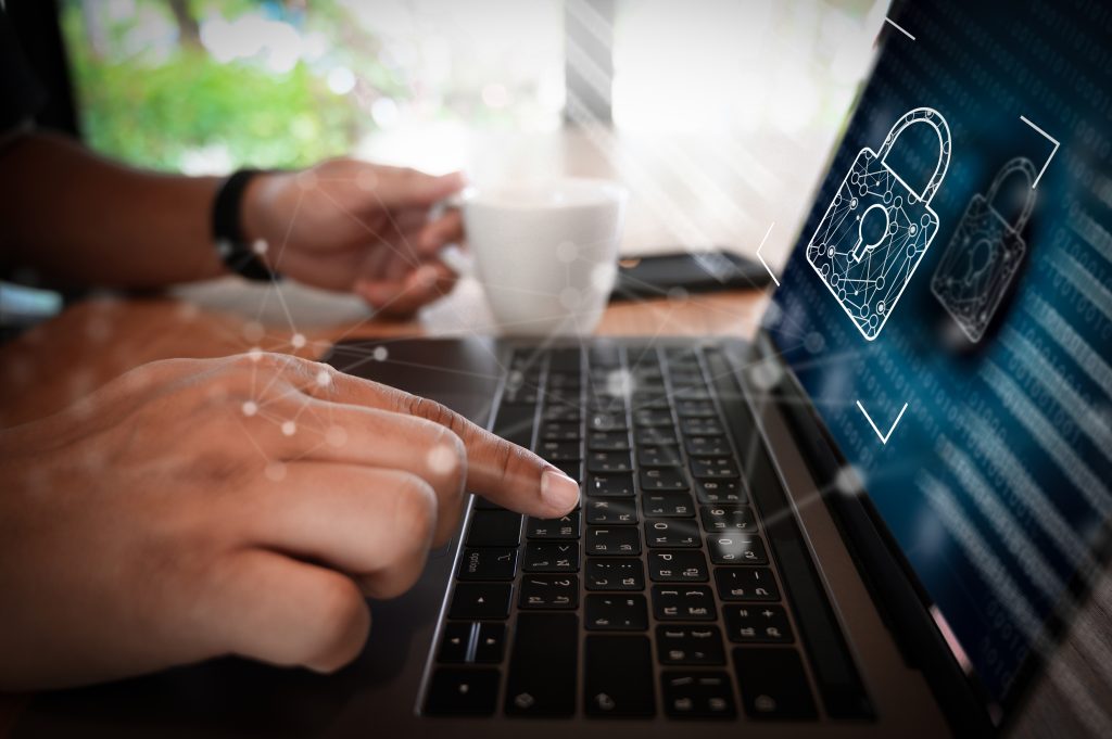 Dłonie na klawiaturze laptopa z symbolem zamka na ekranie, ilustracja do wpisu poruszającego tematy: offboarding IT i konta widmo